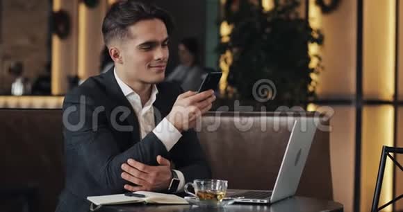在咖啡馆工作的年轻商人使用智能手机和笔记本电脑的自由职业者成功的职业生涯IT自由职业者的概念视频的预览图