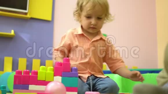 美丽的金发幼儿园可爱的幼儿玩多色积木在幼儿园儿童发展视频的预览图