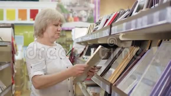 老年妇女在超市选择照片或相框在商店里购物高级女性视频的预览图