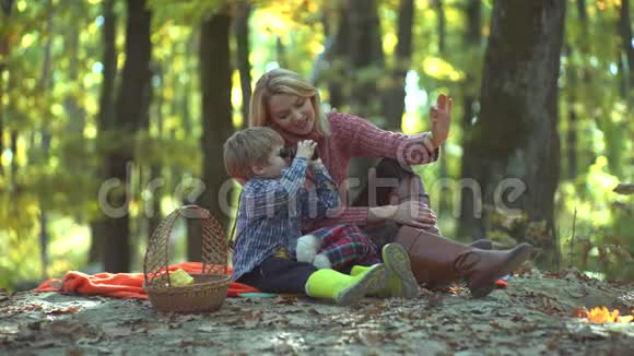 微笑的母亲和孩子在秋天公园玩五彩缤纷的秋女肖像年轻父母和子女视频的预览图