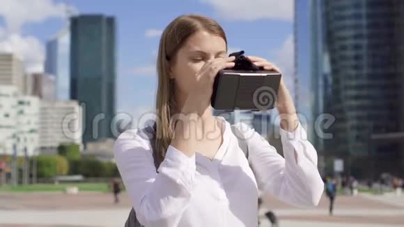 女人站在商业区用虚拟现实眼镜背景摩天大楼视频的预览图