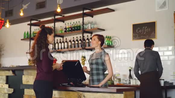 年轻人在当地漂亮的咖啡馆里买咖啡用智能手机付款而友好的员工则打招呼视频的预览图