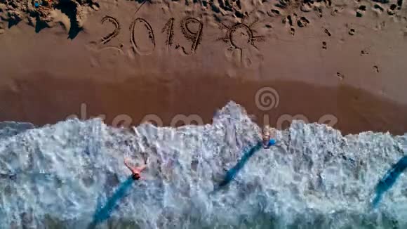 快乐的孩子们在海滩上玩耍写在沙滩上的2019年新年视频的预览图