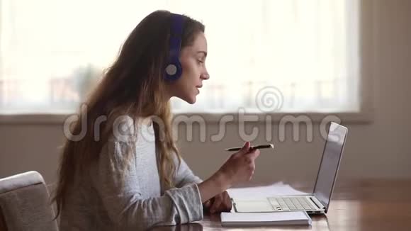 认真的女学生戴着耳机在网上学习视频的预览图