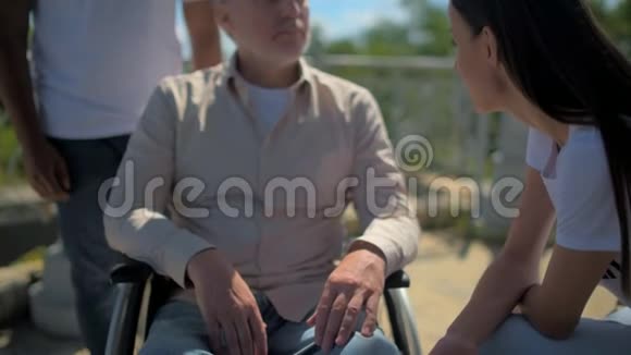一位快乐的女性志愿者手牵着一个退休的轮椅男子视频的预览图