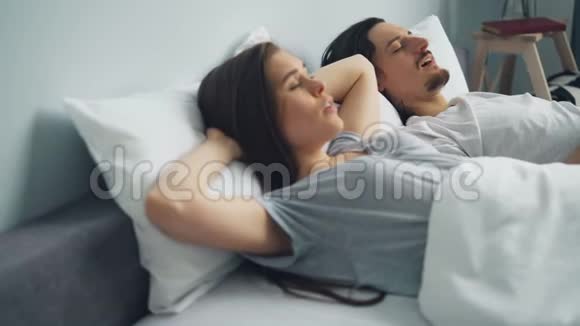 当男友睡在床上打呼噜时带枕头的愤怒女人捂着头视频的预览图