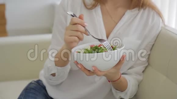 年轻女子坐在室内的沙发上吃沙拉视频的预览图