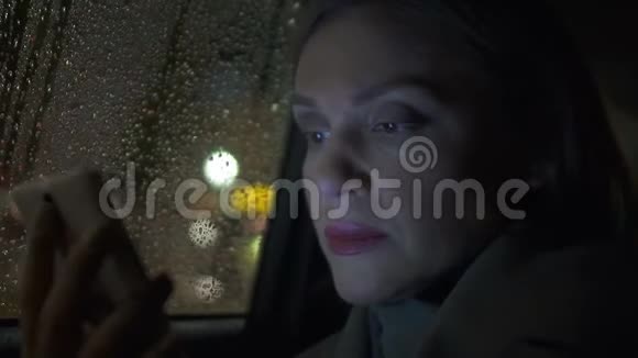 体贴的女士在出租车上看书在智能手机上在线申请聊天视频的预览图