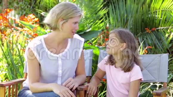 母亲和女儿坐在花园的椅子上聊天视频的预览图