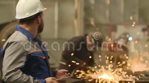 在重工业工厂使用平板电脑的工程师打磨火花背景视频的预览图