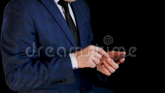 穿西装的商人在他的智能手机上工作露出微笑手指触摸触摸屏打字管理视频的预览图