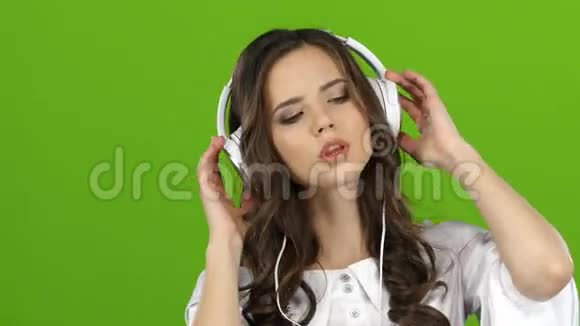 女孩通过耳机欣赏音乐并一起唱歌绿色屏幕关门视频的预览图