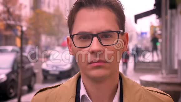 一个成年白种人的特写镜头面对镜头戴着眼镜向前看站在路边的街道上经过视频的预览图