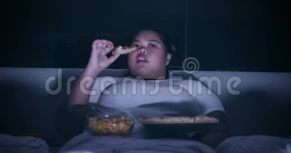 超重女人晚上在床上吃披萨视频的预览图