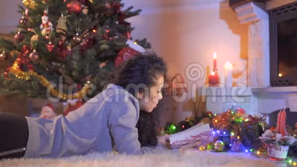 美丽的黑发女人在圣诞树附近看书视频的预览图