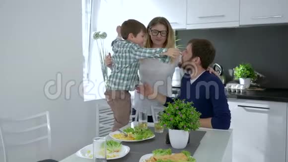 家庭拥抱快乐的父母在餐桌上与孩子拥抱视频的预览图