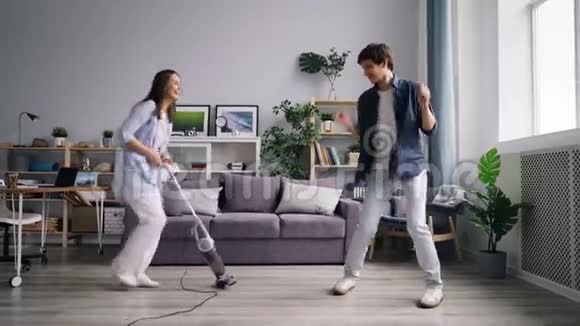 在家里用吸尘器做家务时年轻的家庭舞蹈唱歌视频的预览图