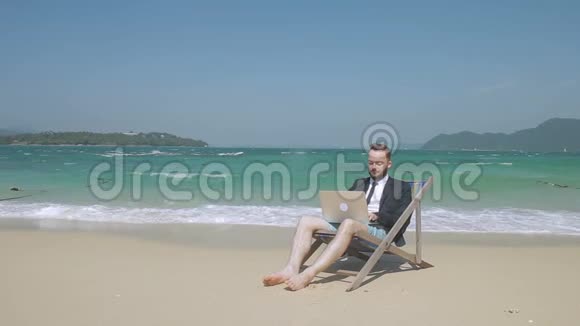 在海滩上笔记本电脑后面的年轻人在度假时做生意视频的预览图