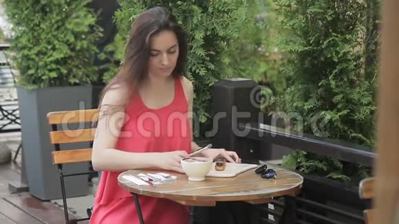 迷人的女人在夏天的咖啡馆打电话拍照食物视频的预览图