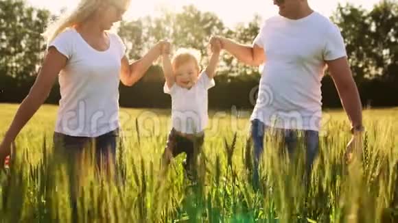 一个年轻的家庭有一个孩子在田野里奔跑小麦穗摆动着一个男孩他怀里笑着笑着视频的预览图