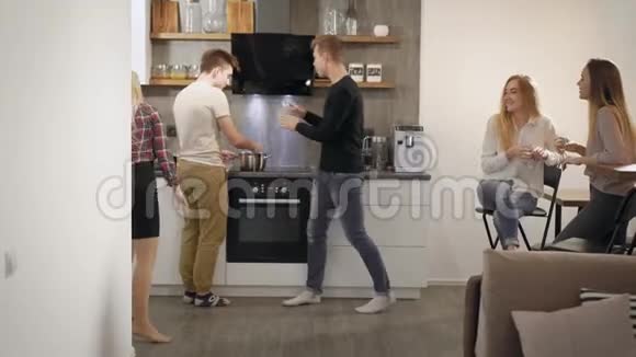 快乐的青少年男孩和女孩晚上在公寓的厨房里玩喝酒视频的预览图