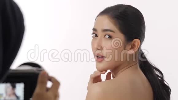 幕后拍摄的美丽的年轻亚洲女子模特被录制在一个摄像机视频的预览图