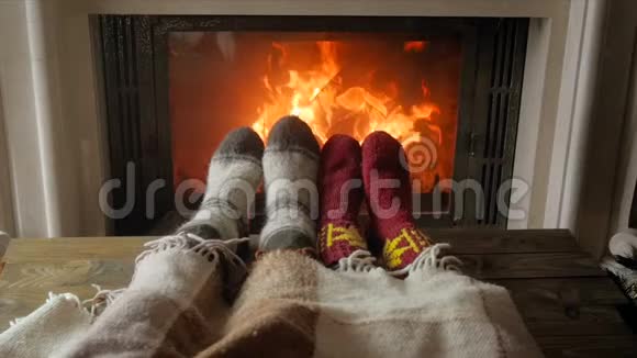 特写慢动作视频情侣们穿着温暖的袜子躺在客厅的毯子下面壁炉燃烧视频的预览图