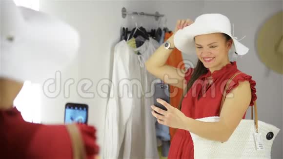 幸福的年轻女子站在服装店的化妆室里女孩在更衣室附近拍照视频的预览图
