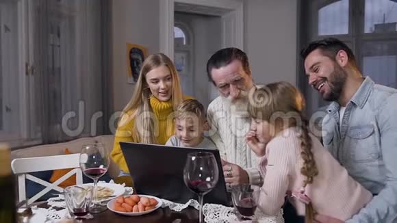 幸福快乐的家庭在电脑上观看美丽的照片这些照片显示他们尊敬的老爷爷坐在一起视频的预览图