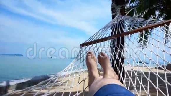 视频POV的脚摆动在吊床上椰子树在泰国海滩放松视频的预览图