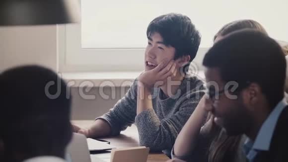 在多民族办公会议上与同事一起听笑特写快乐的日本年轻员工视频的预览图