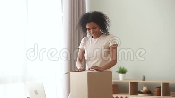 高兴兴奋的非洲裔美国妇女客户在家打开包裹视频的预览图