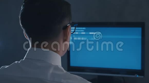 夜间办公室电脑显示器眼镜编程专业程序员的后视图视频的预览图