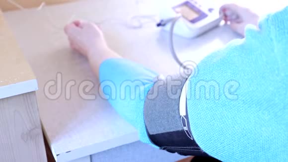 一位在家测量血压的老年妇女的手一个光度计的袖口视频的预览图