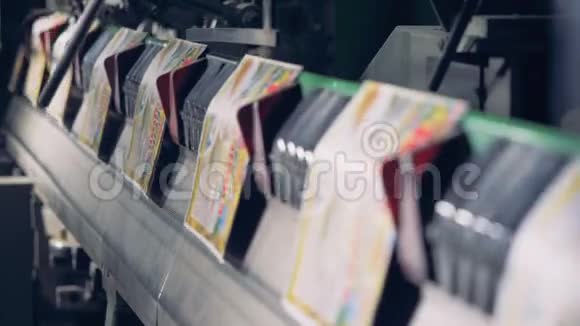一排五颜六色的印刷卡片沿着传送带移动视频的预览图