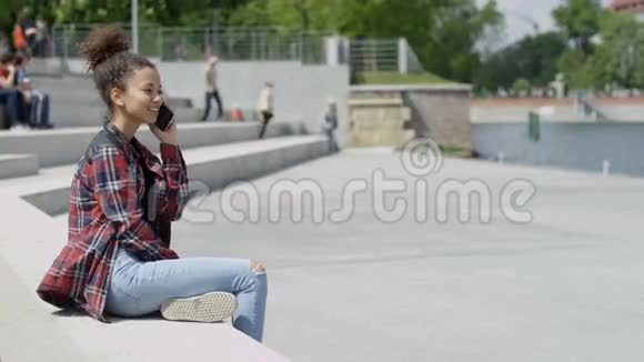 年轻漂亮的美国黑人女孩在户外用智能手机说话视频的预览图