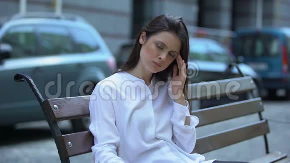 坐在长凳上精疲力竭的妇女患有偏头痛健康问题视频的预览图