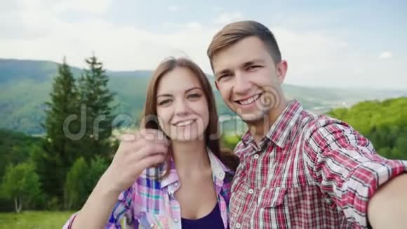 快乐夫妇在美丽的山脉背景上自拍华丽的假期和假期4K慢动作视频的预览图