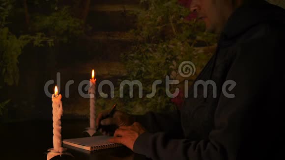 白人商人或学生晚上坐在桌边烛光照亮笔记本写信给你视频的预览图