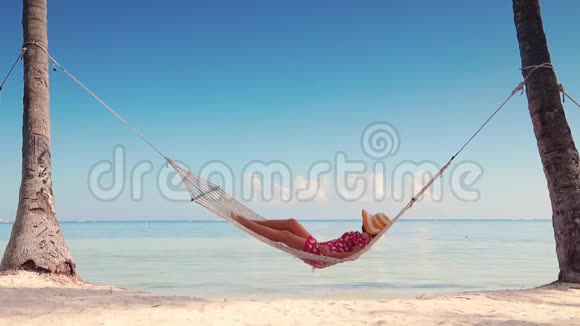 女孩在热带岛屿海滩的吊床上放松暑假假期视频的预览图