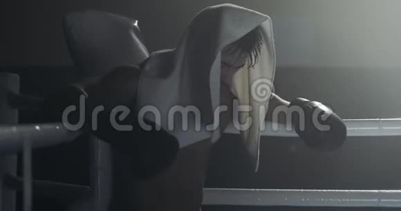 疲惫的男拳手拿着毛巾休息在拳场边缘拳击手经过艰苦训练后休息视频的预览图