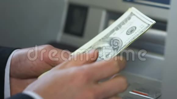 在自动取款机附近数美元把钱放进钱包银行的商人视频的预览图
