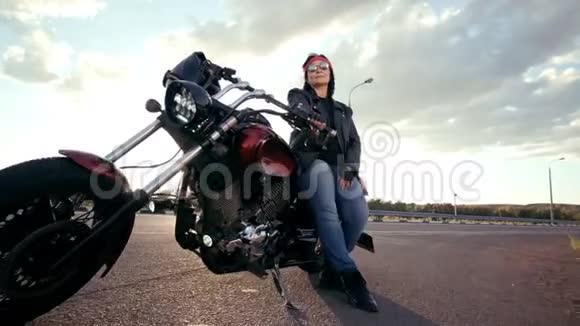穿着皮夹克和手套坐在他酷酷的摩托车上的比基尼老妇人那个女人戴着圆眼镜戴着红色的视频的预览图