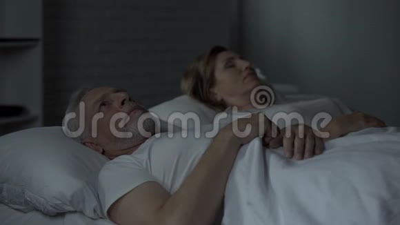 躺在床上的老人醒着看着睡在他身边的女人烦恼视频的预览图