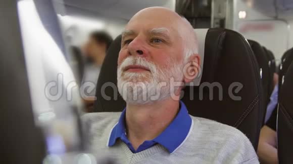 白天坐飞机的老人在湍流中男性在靠近窗户时感到疲倦视频的预览图
