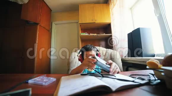 一个小男孩把盒式磁带放进转盘里听着耳机里的音乐俄罗斯的旧内饰视频的预览图