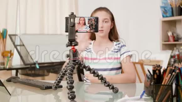 三脚架上的智能手机拍摄一个年轻女孩在说话视频的预览图