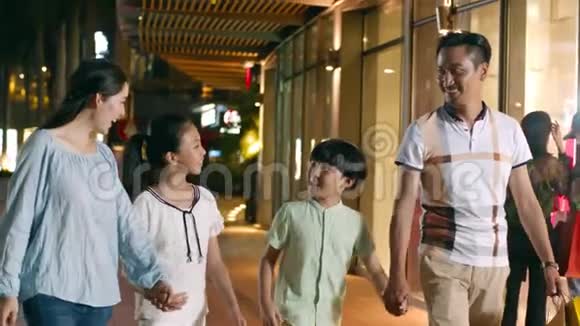 亚洲一家4口人夜间慢动作在购物中心外散步和购物视频的预览图