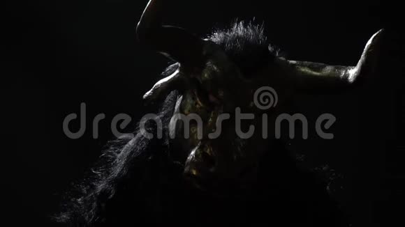 戴着牛头怪面具的人坐在黑暗中视频的预览图