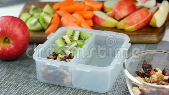 女人把健康的水果和坚果零食放进饭盒里视频的预览图